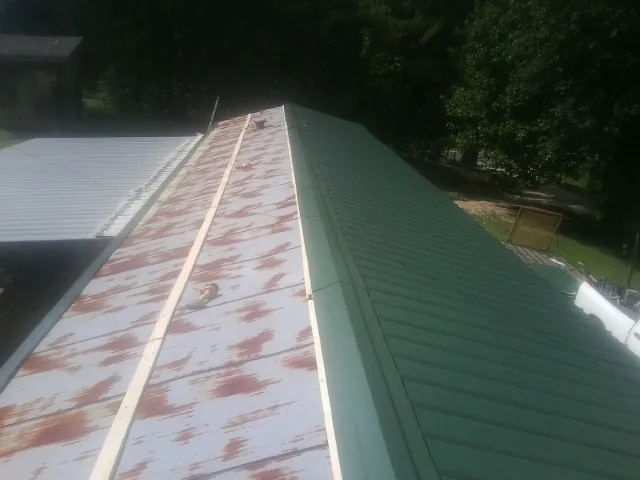 Old rusted panels beside newly installed green metal roofing — Wind Damage Roof Repair by Roofing Brothers in Stony Creek