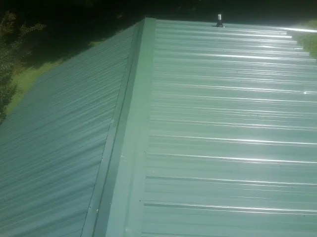 New green metal panels meeting at the ridge of a roof — Flat Roof Repair work by our crew in Stony Creek