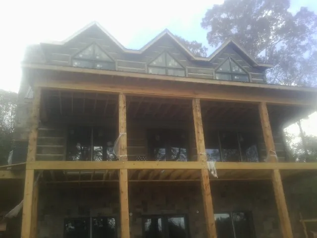 Dormers and porch framing on a large log home under construction — Roof Coating work by our crew in Stony Creek