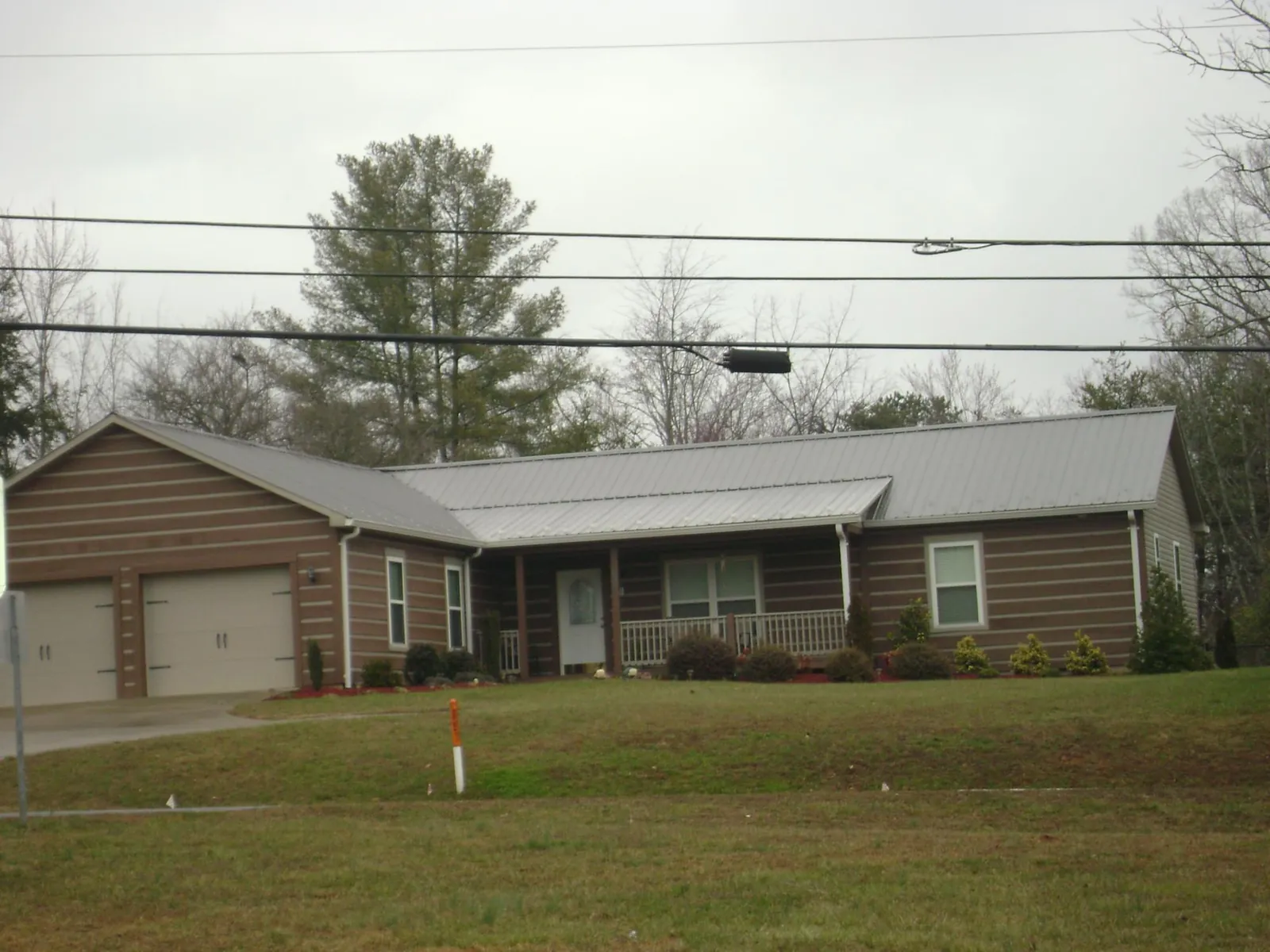 Gray metal roof on a log sided ranch home with a front porch in Stony Creek