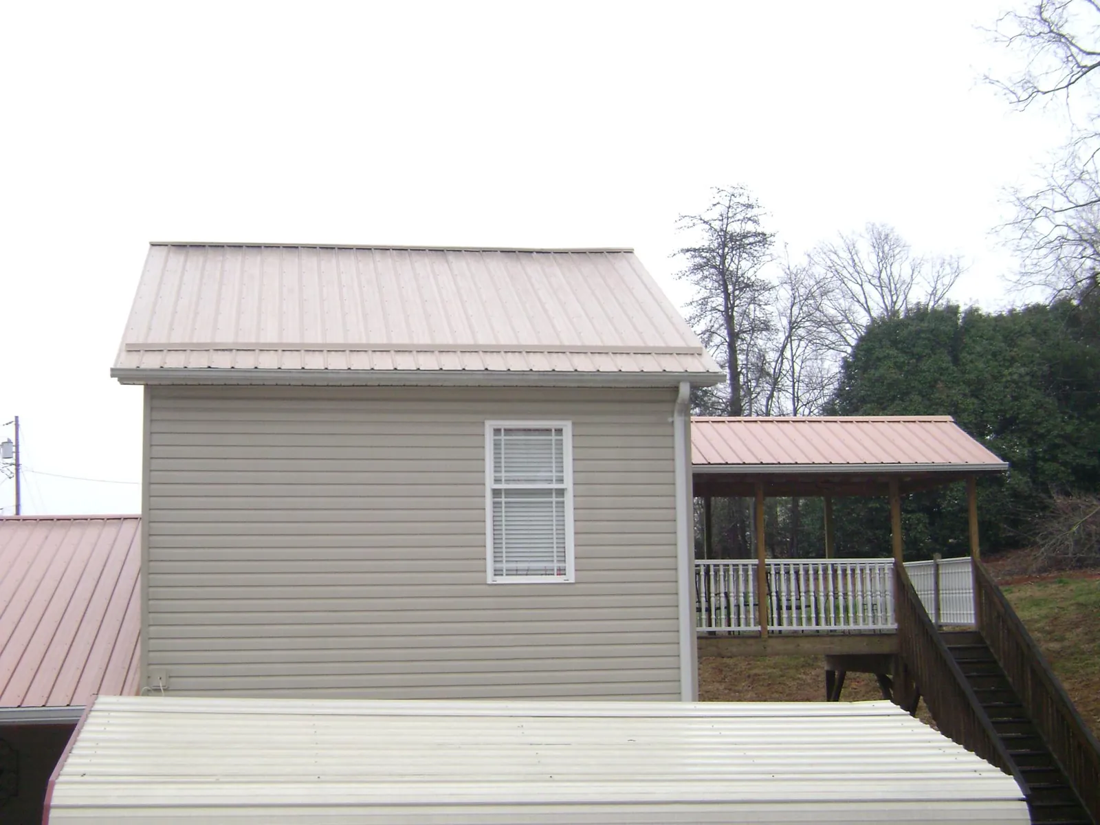 Tan metal roofs on a two story addition and attached porch, from a Roof Replacement job in Stony Creek