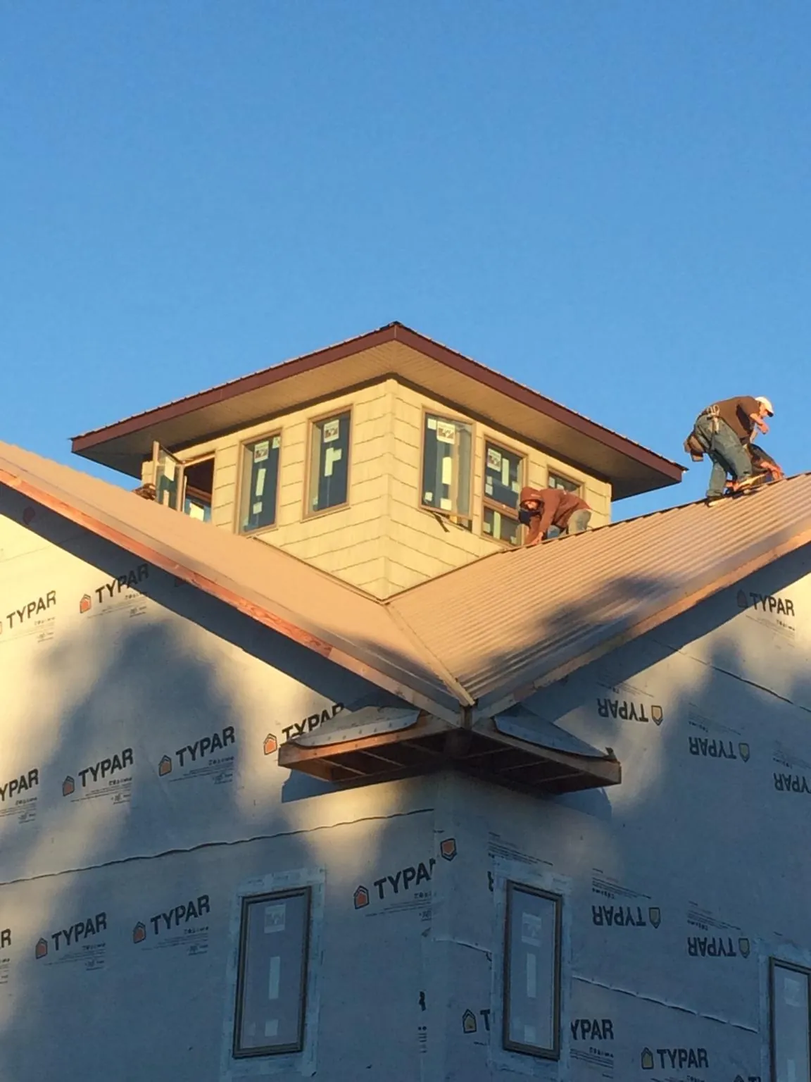Roofers working around a rooftop cupola on a new metal roof at sunset — Roof Waterproofing in Stony Creek by Roofing Brothers